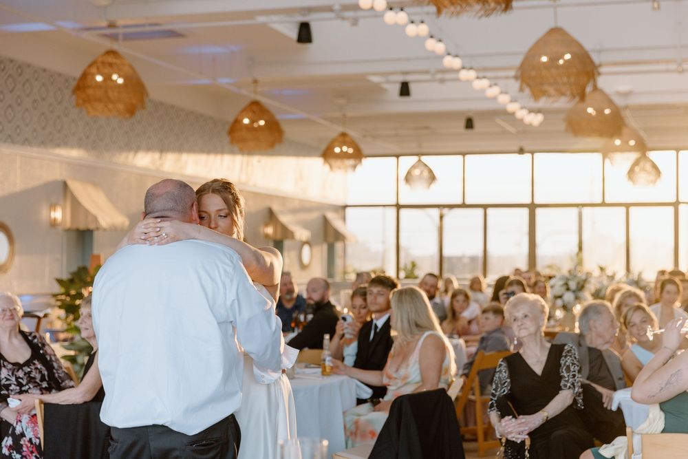 Wedding celebration with guests dancing under warm hanging lights in an elegant venue.