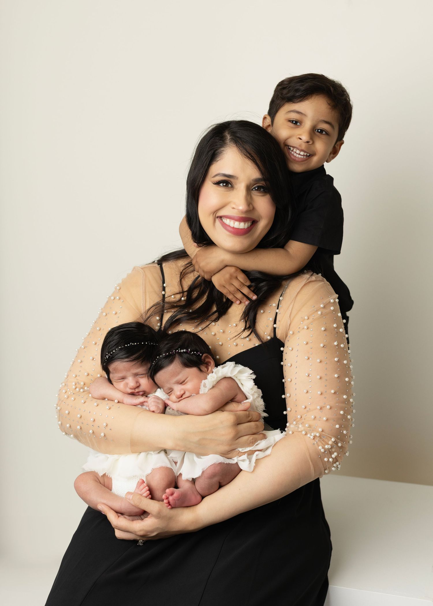 Mom with her newborn twins and her older son hugs her around his neck. A happy and loved mom. Elizabeth Lang Photography