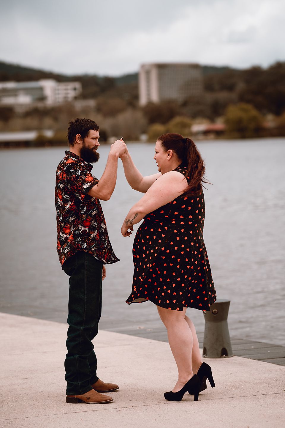 A couple embracing on a dock by the water during a romantic engagement photo session.