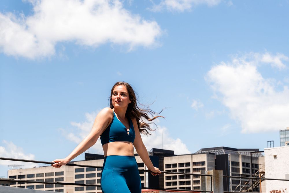 Woman exercising on a rooftop with urban buildings in the background.