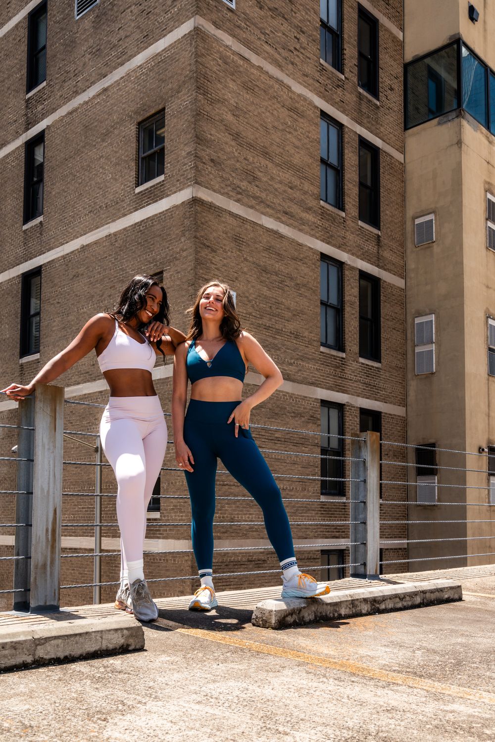Two friends stretching and exercising together on an urban rooftop.