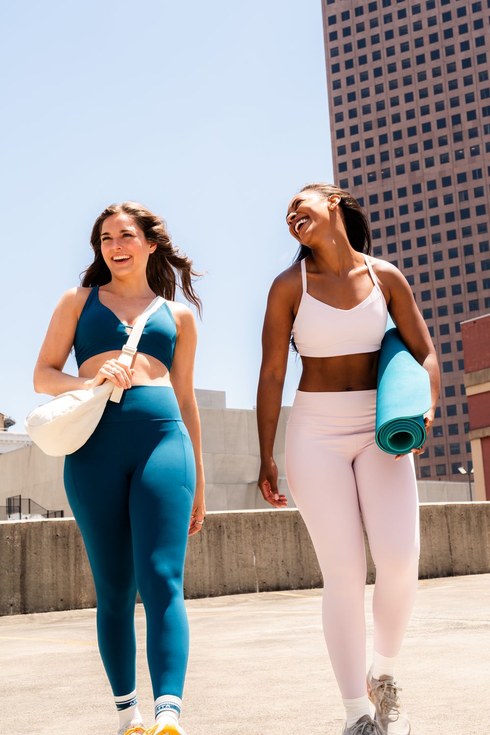Women in coordinated workout attire exercising together on a sunny rooftop.