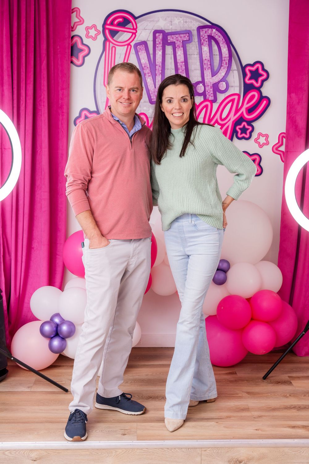 Posed couple's portrait in front of business branding.