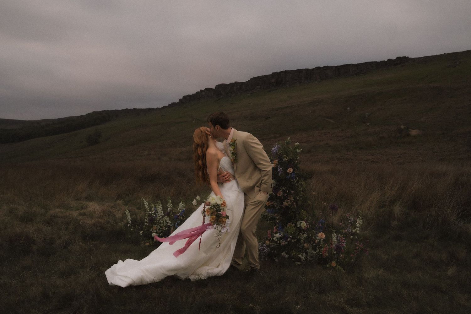 An elopement wedding ceremony with an intimate moment against a backdrop of rolling green hills at sunset at Stanage Edge the Peak District