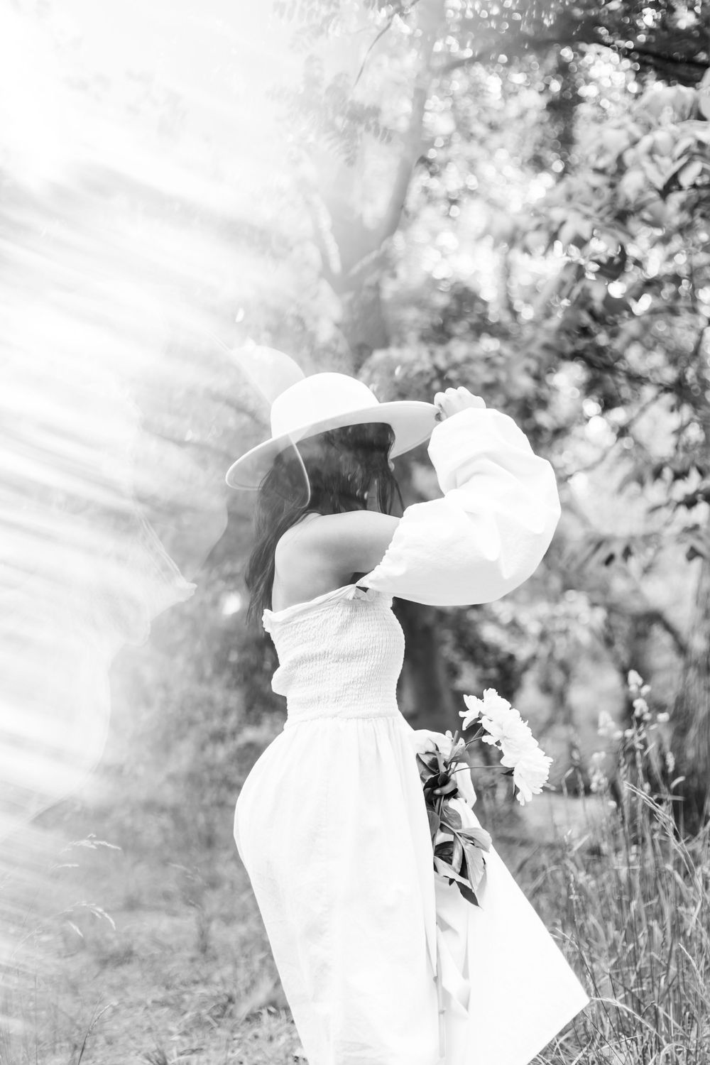 A series of black and white artistic portraits of someone in white clothing captured in an outdoor garden setting.