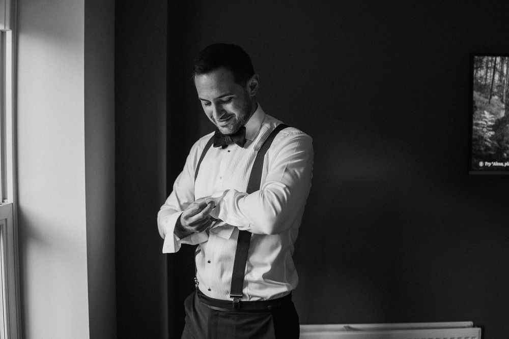 A series of candid black and white photos showing a person in formal attire checking their phone near a window.