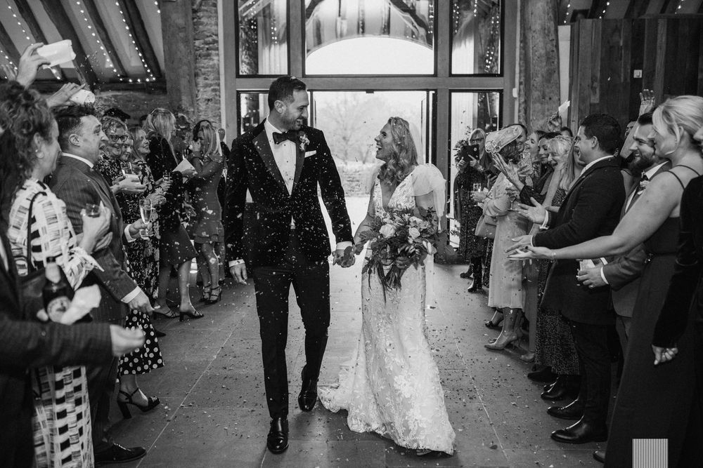 Wedding guests form a corridor and wave sparklers as the newlywed couple walks through during an evening celebration.