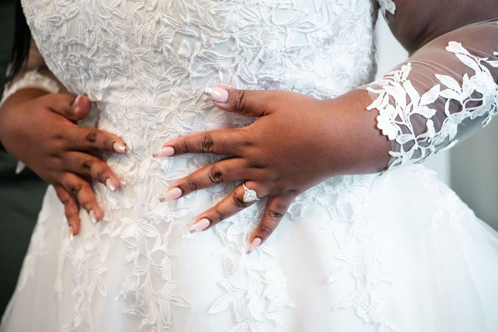 Close-up details of white lace wedding dress fabric with delicate floral patterns and beaded embellishments.