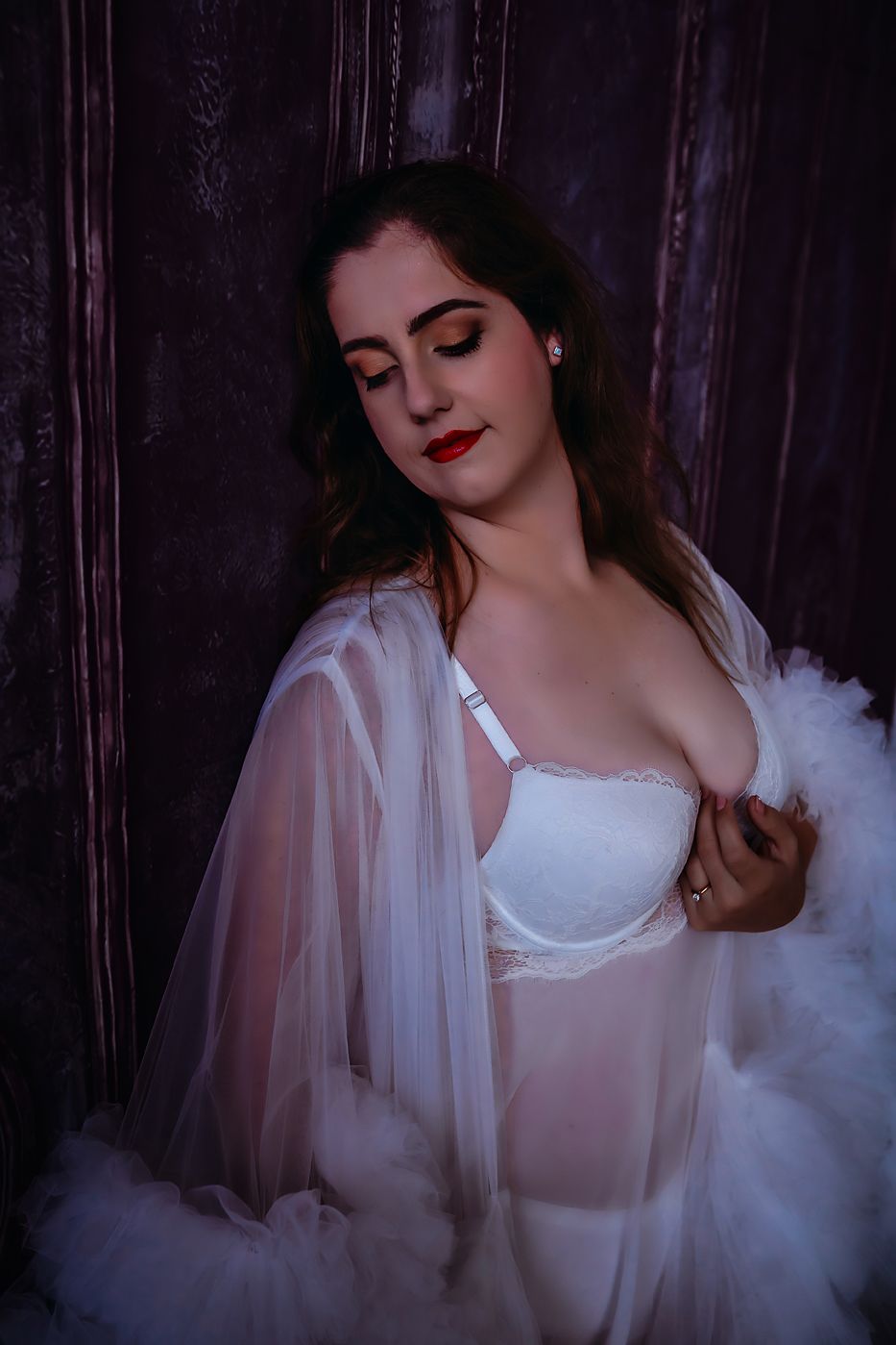 Artistic boudoir portrait with sheer robe and white lingerie in moody lighting against dark background.