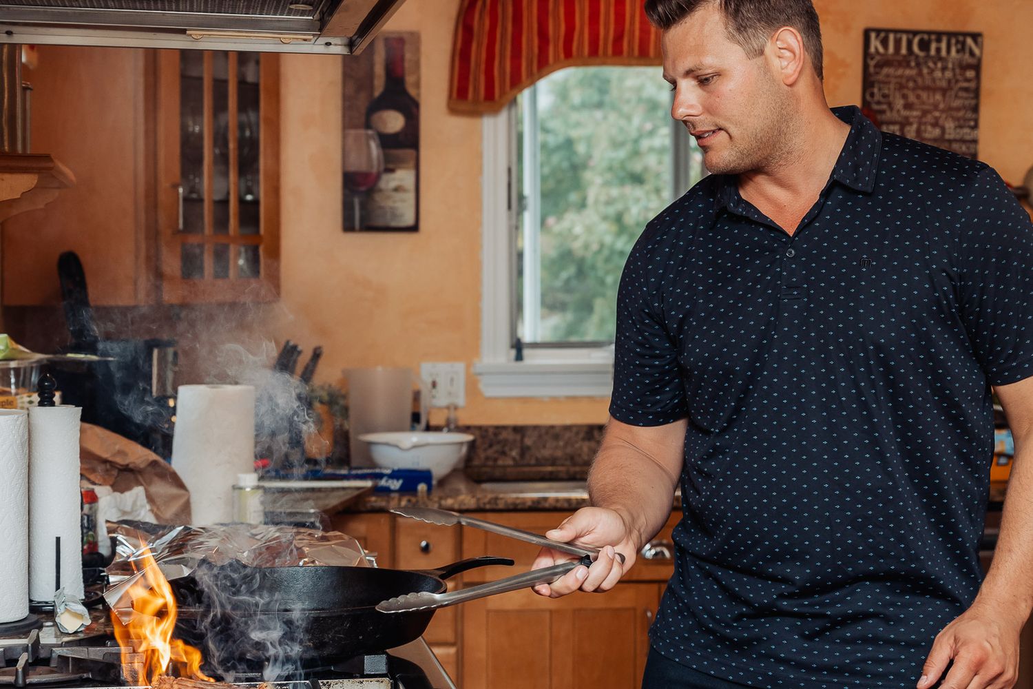 Person cooking with flames visible on stovetop in modern kitchen.