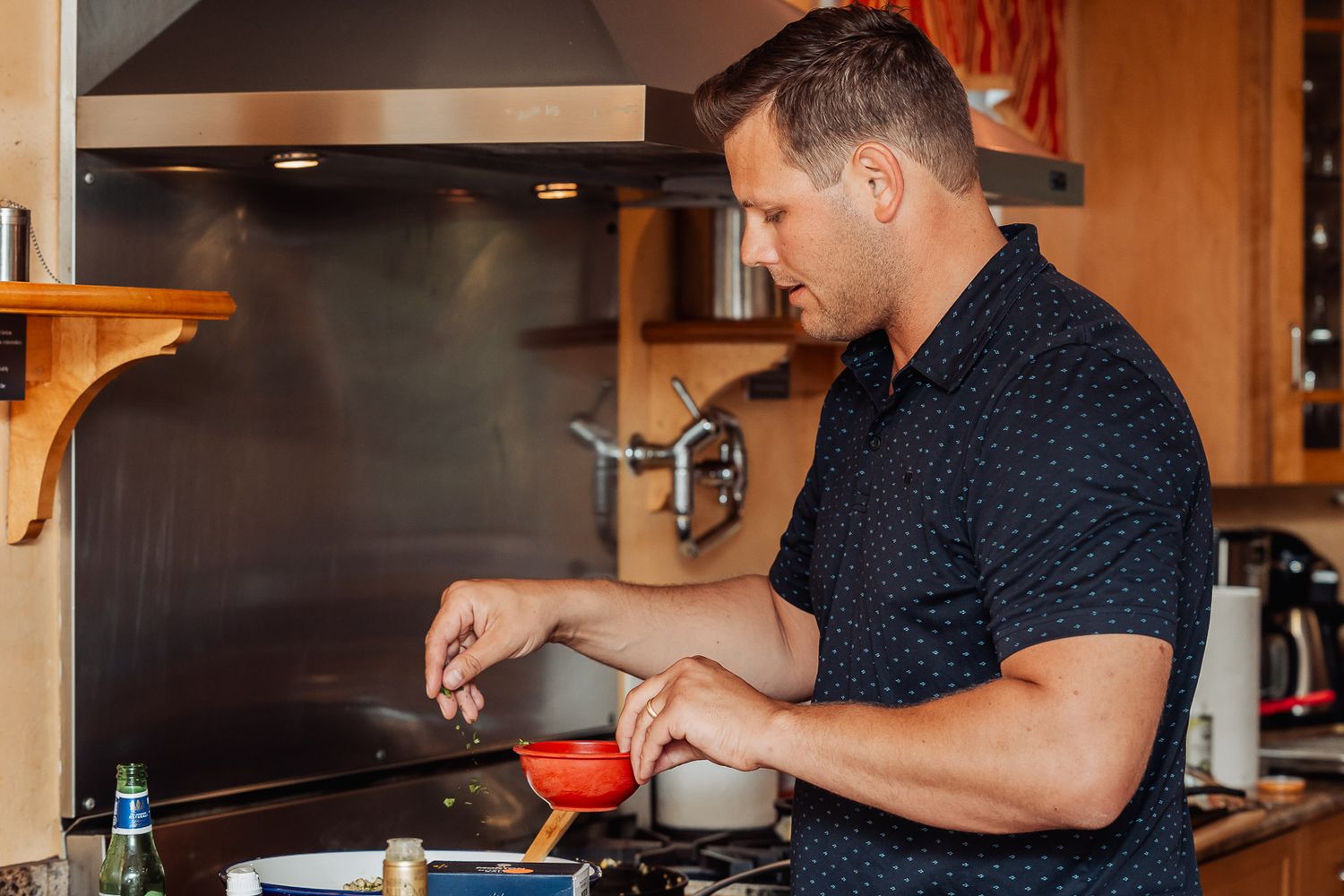 Person in navy polka dot shirt stirring food while cooking in kitchen.