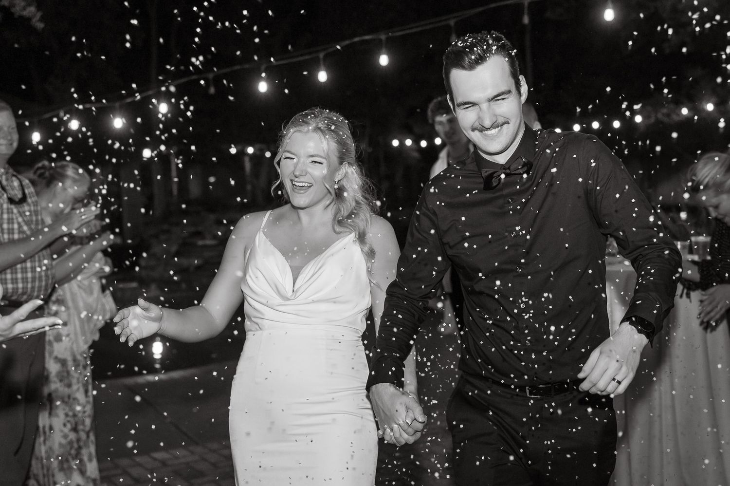 A wedding couple celebrates under falling bio-degradable confetti during their nighttime reception.