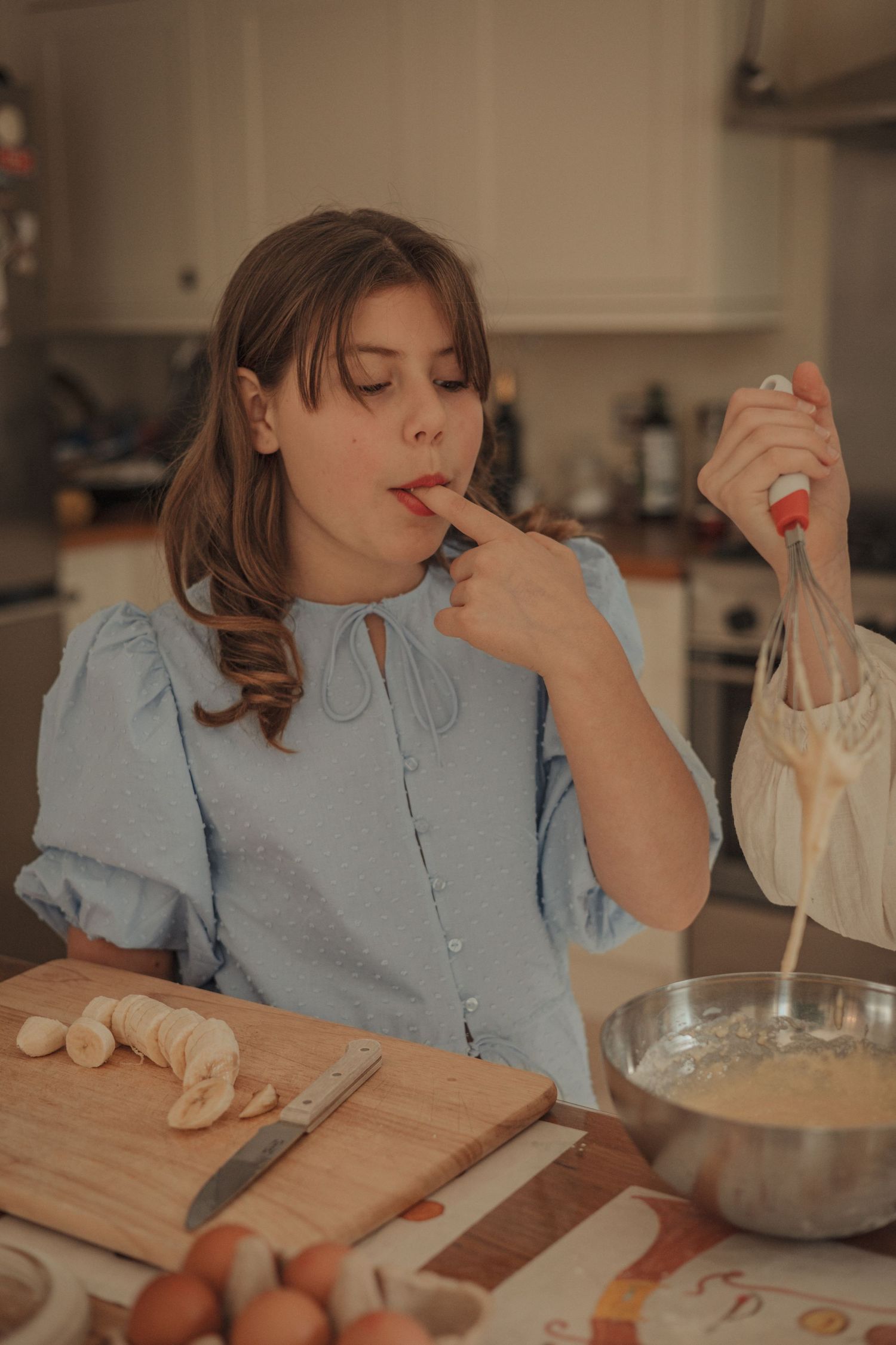 girls baking, one tasting the mix, colour,vintage warm vibe, natural light, grainy, family photography in Norfolk