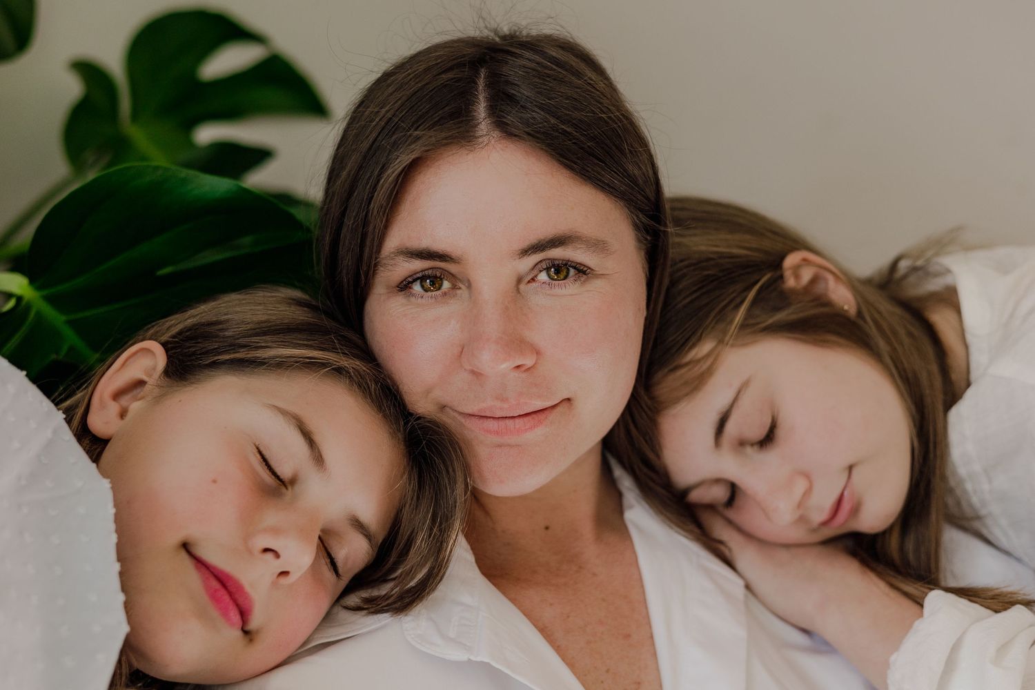 mum and daughters resting heads on her , light and airy, motherhood in Norfolk, colour, natural light, muted tones