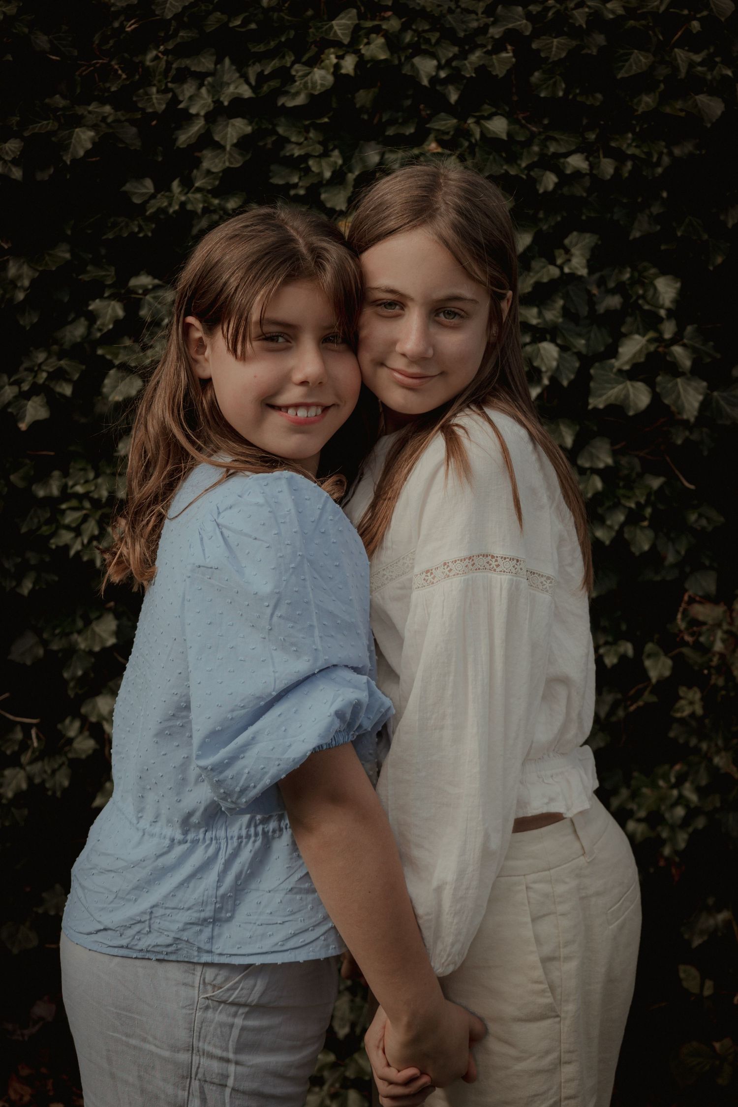 sisters facing each other holding hands in the garden smiling ,norfolk, motherhood session