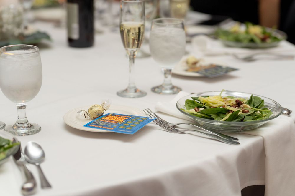 Elegant table setting with white tablecloth, salad plate, champagne glass, and cutlery at a formal dining event.
