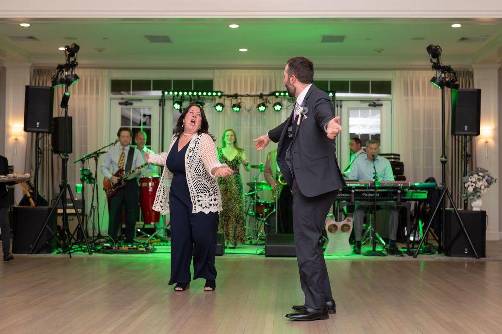 Couple dancing at a special event with a live band performing under green stage lighting on dance floor.