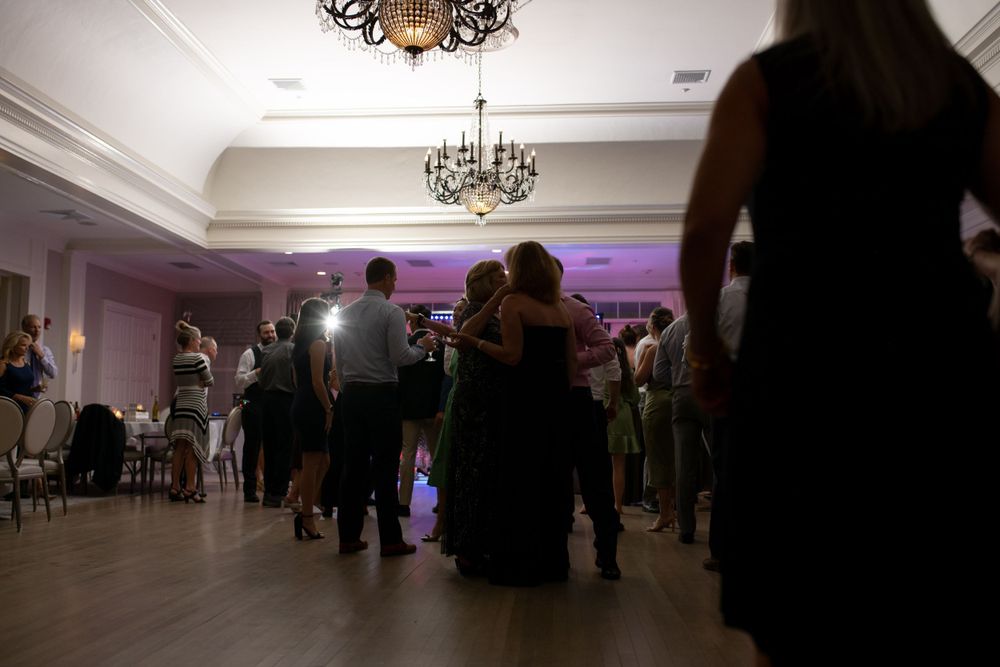 Silhouettes of couples dancing at an elegant ballroom event under crystal chandeliers with purple accent lighting.