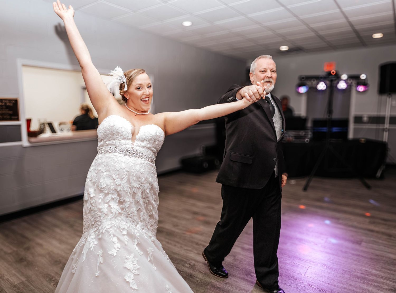 Wedding reception dance scene with bride in white gown striking dramatic pose on dance floor.