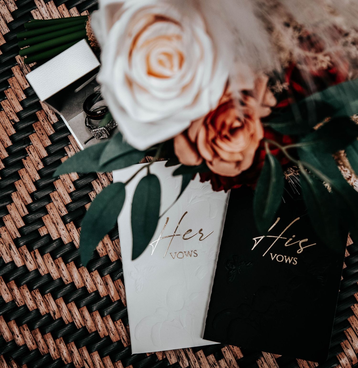 Wedding vow books labeled 'His' and 'Hers' with roses on textured surface.