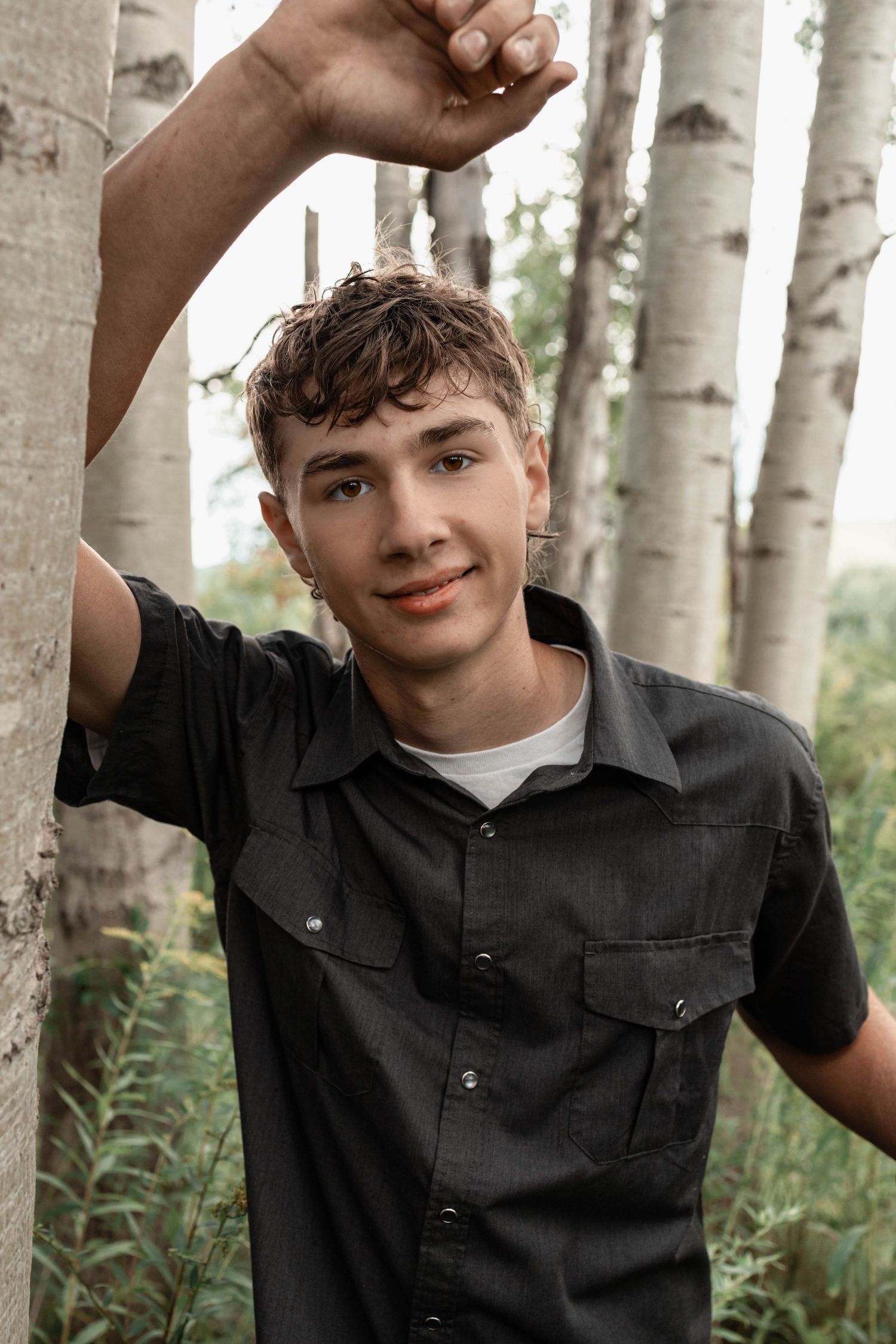 Outdoor portrait in a birch forest with natural lighting and casual attire.