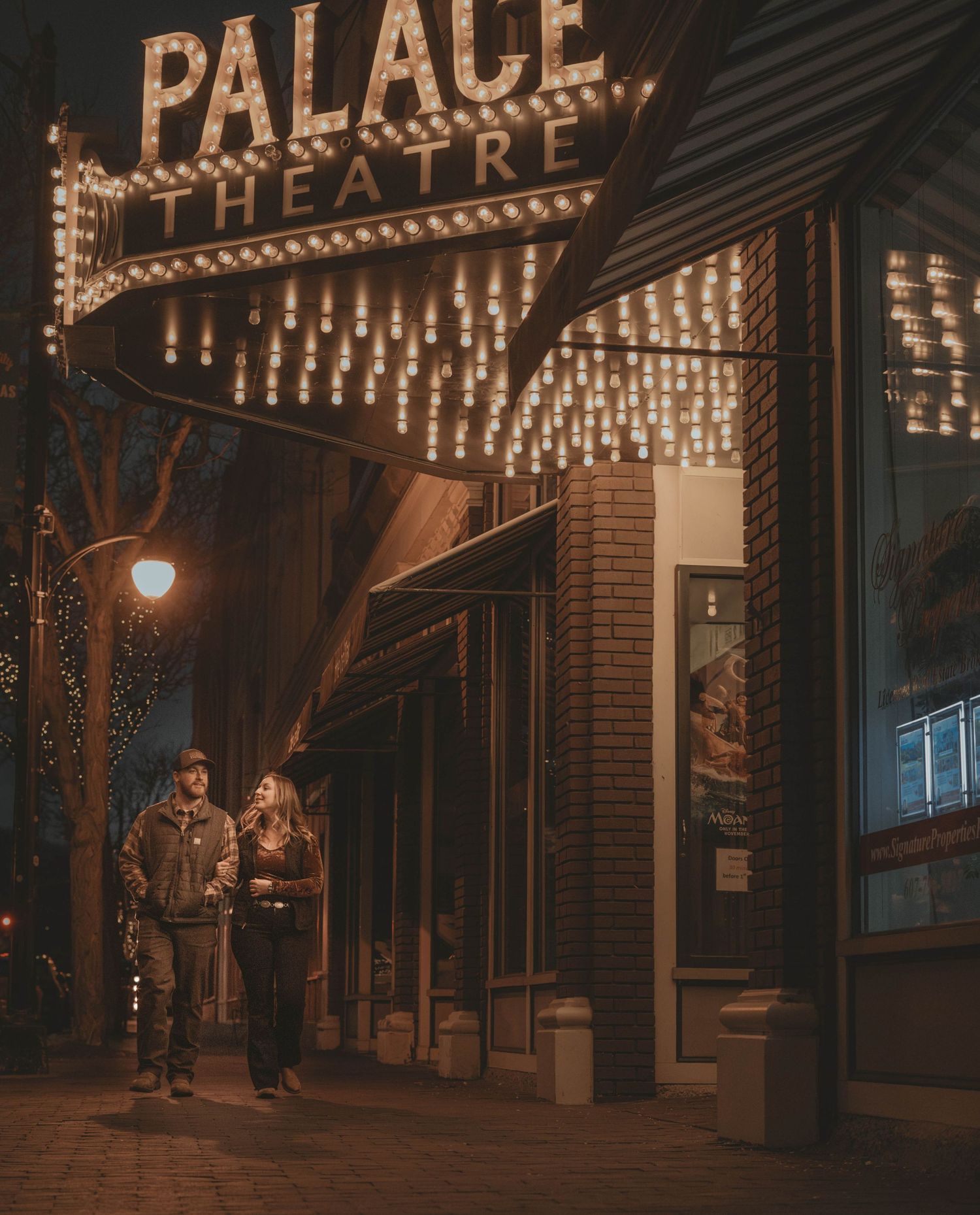Illuminated vintage Palace theater marquee glowing warmly at night with decorative lights and ornate architecture.