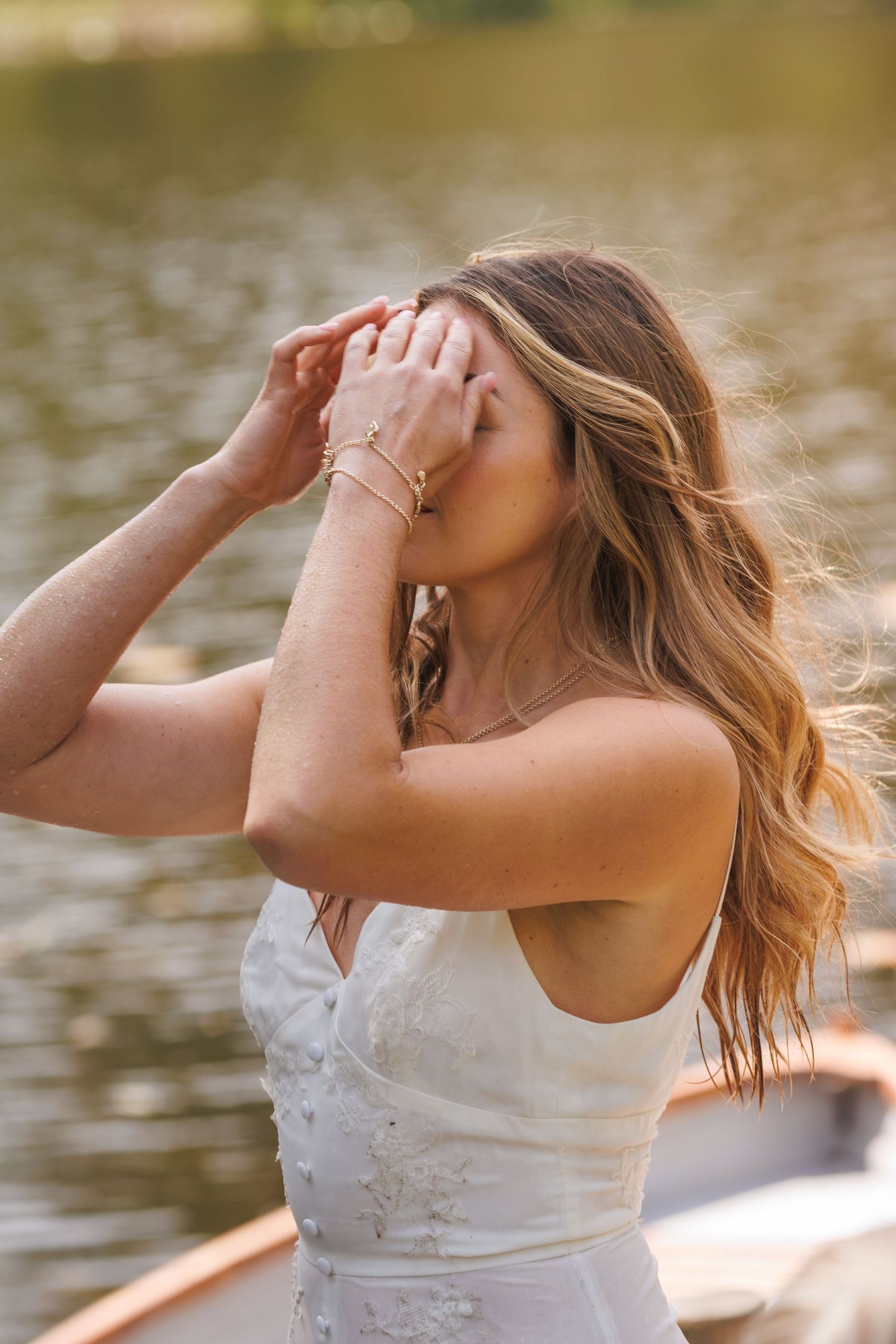 A candid moment captured by the lake in a white wedding dress.