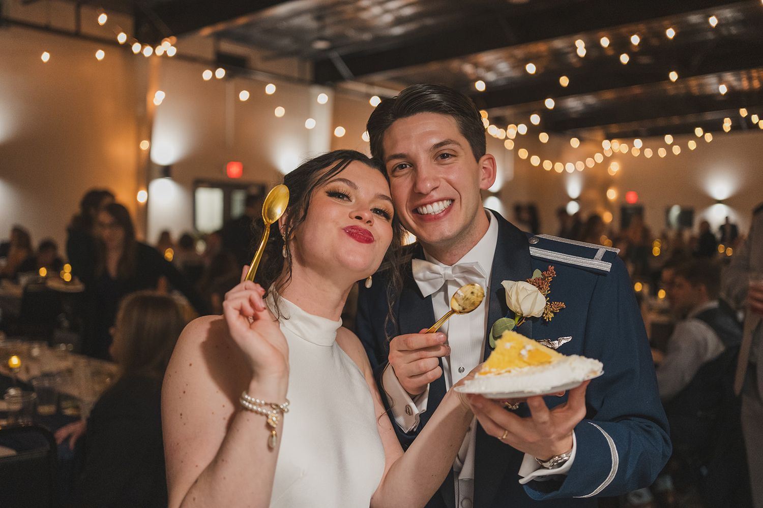 A newlywed couple shares a playful moment while enjoying a slice of wedding cake at their reception.