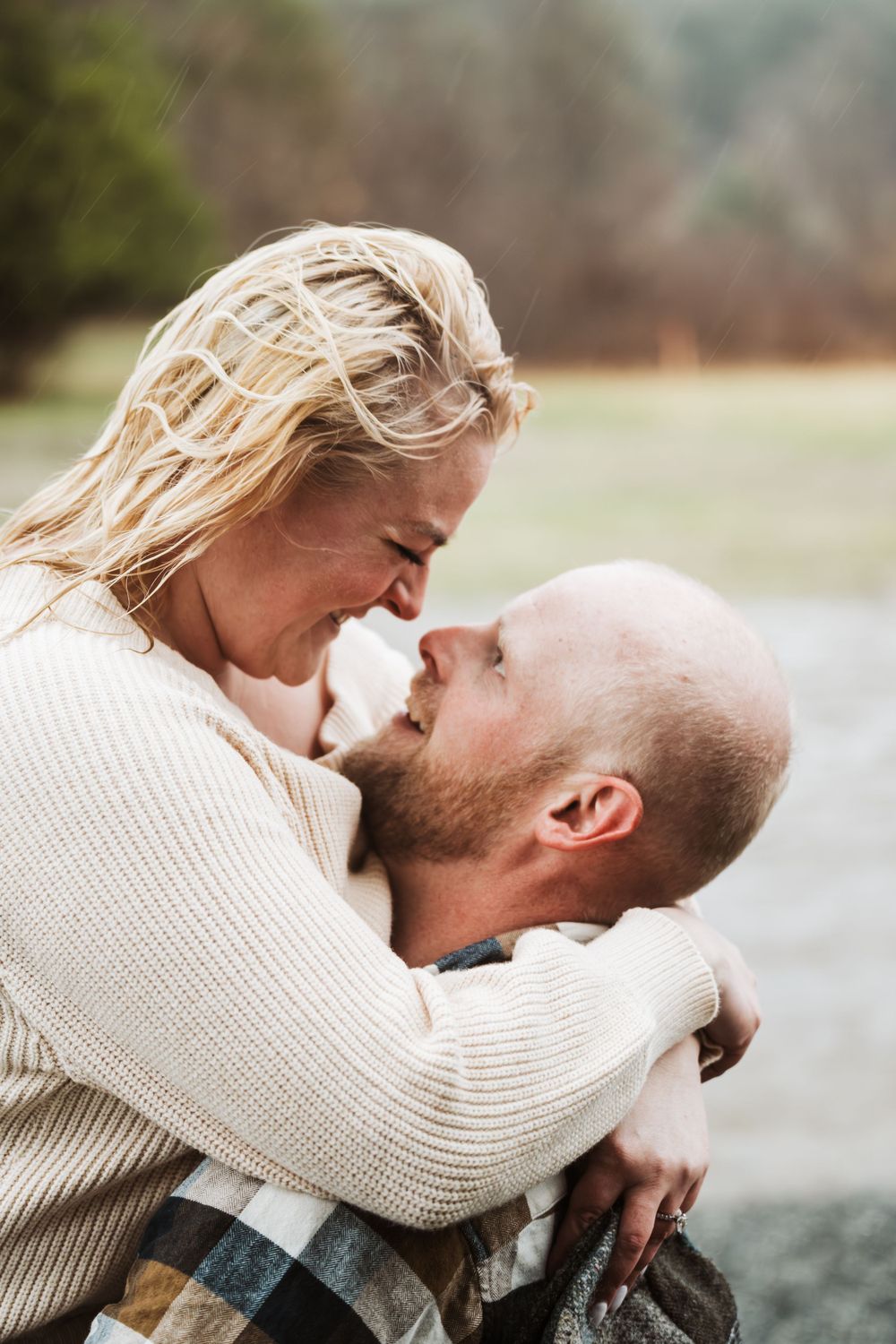 A tender romantic moment between a couple in matching cream sweaters sharing an intimate embrace outdoors.