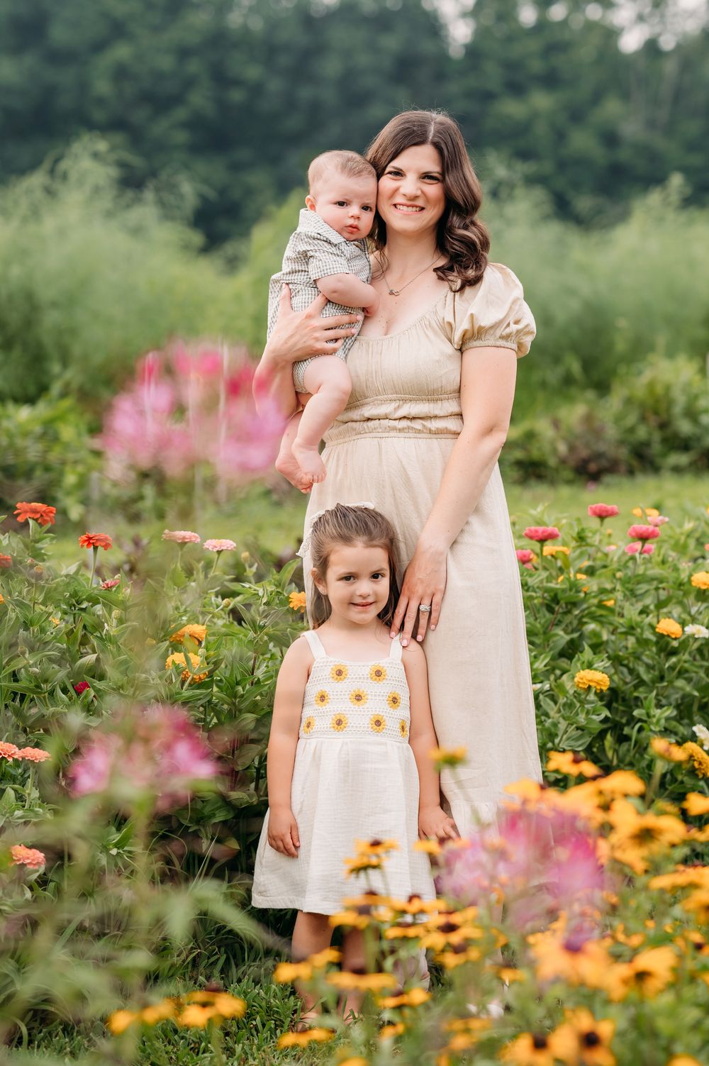 A parent and children stand together in a blooming garden with colorful flowers during summer.