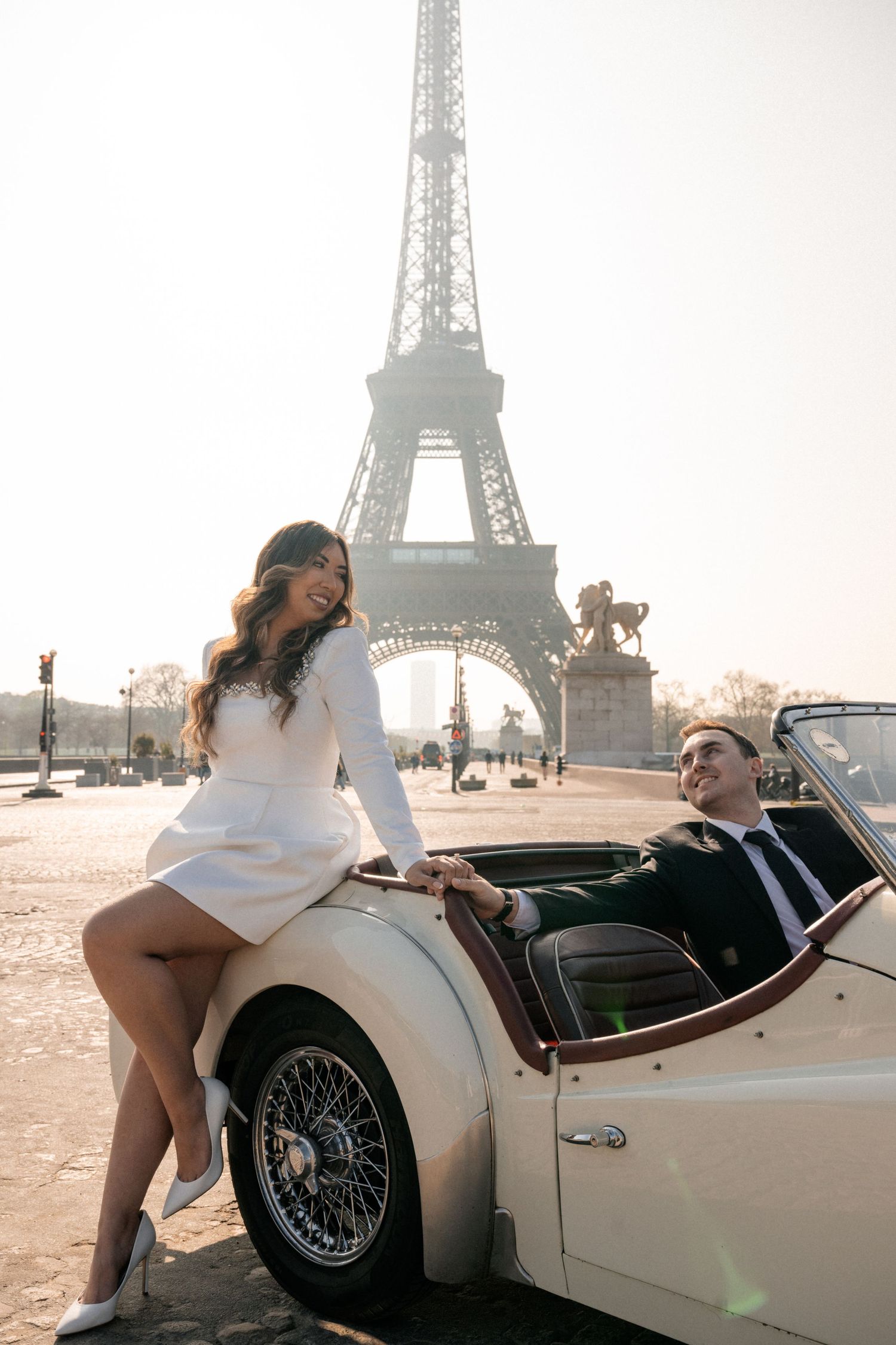A couple shares a special engagement moment on a scenic cliffside overlooking a misty bay.