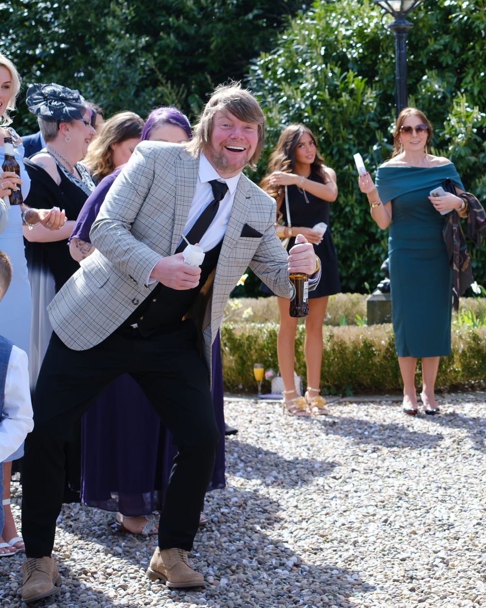 Best man smiling before the confetti line by the stone pillars at the gate of Holdsworth House, Halifax