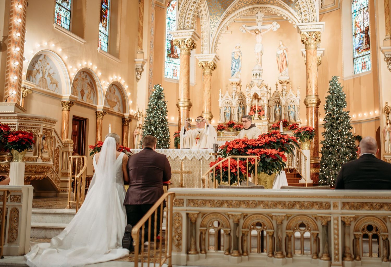 A bride and groom kneel before the altar during the consecration of the Eucharist at the Catholic Wedding Mass in St. Louis, Missouri.