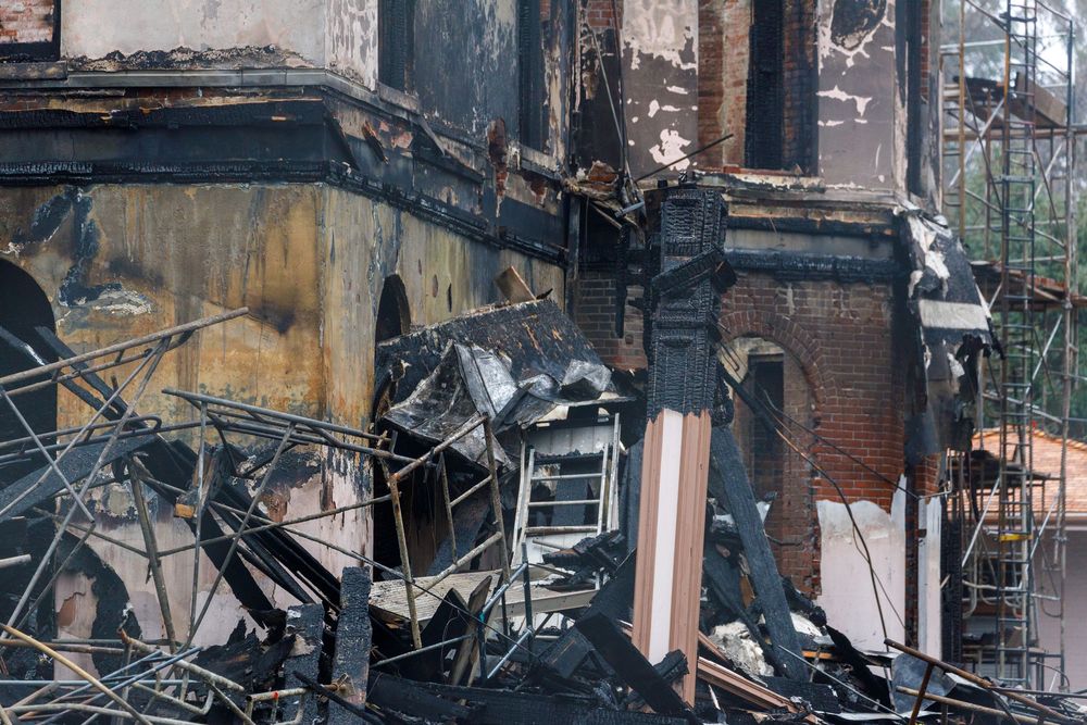 Heavily damaged brick buildings show aftermath of destruction with crumbling walls and exposed structural elements.