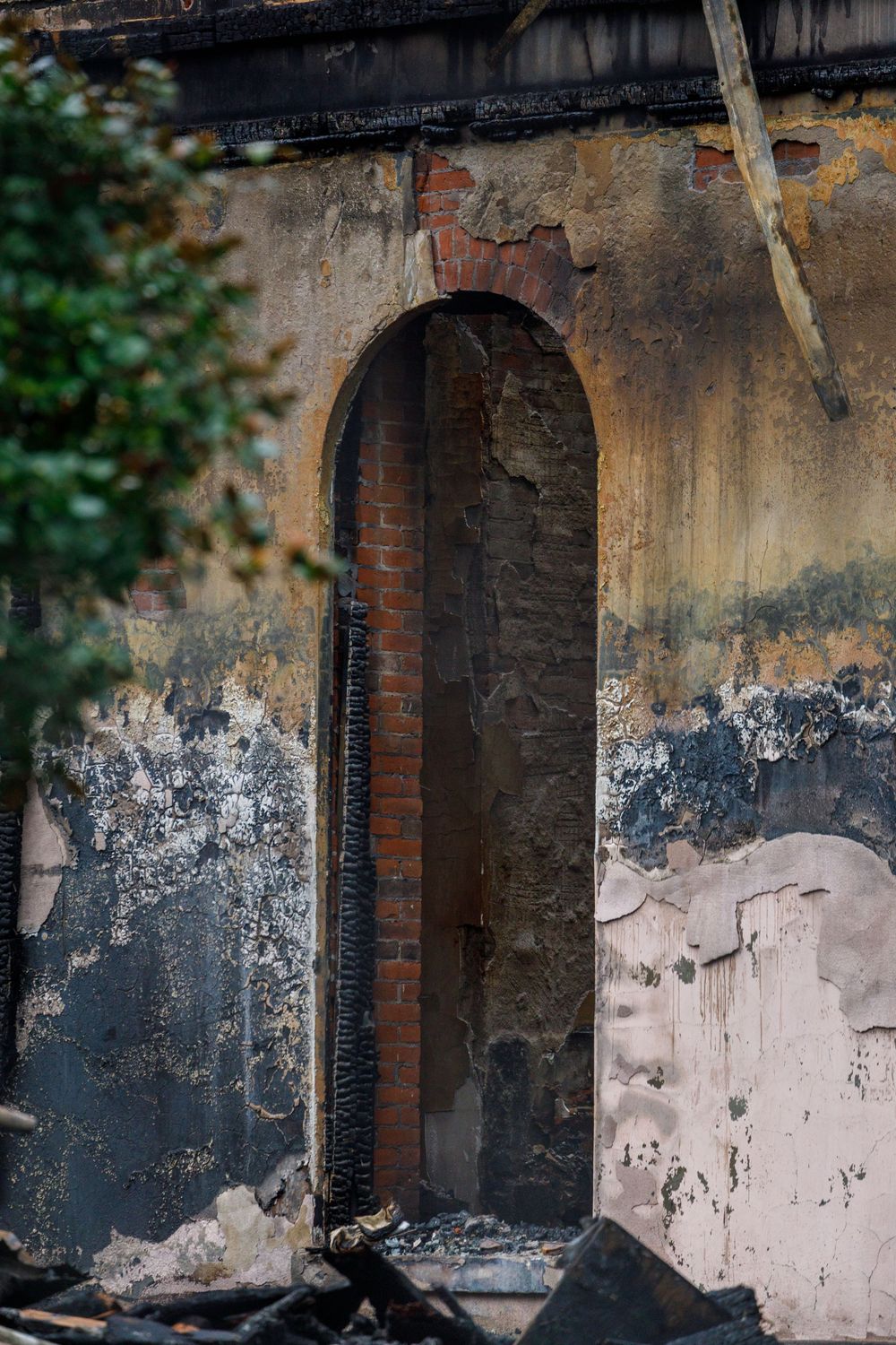 Old weathered brick archway with peeling paint and exposed mortar in a dilapidated wall.