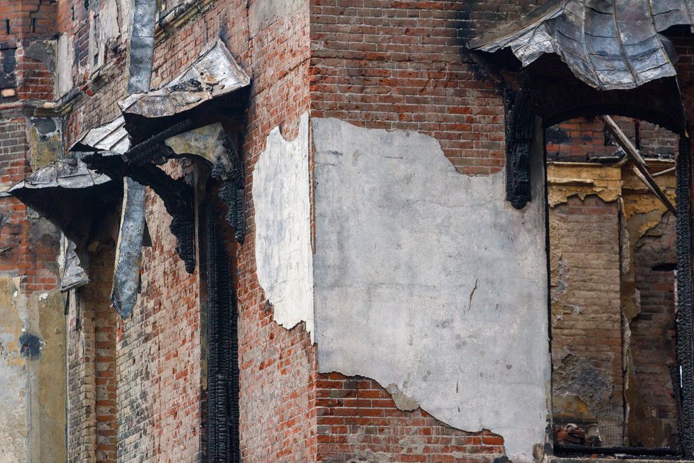 Weathered brick wall with exposed plaster and decaying architectural details shows urban deterioration and decay.