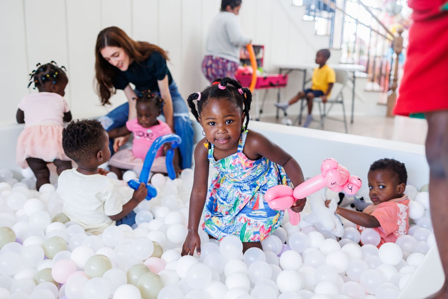 Children playing and smiling in a white ball pit at Bella Cavalli for a first birthday party