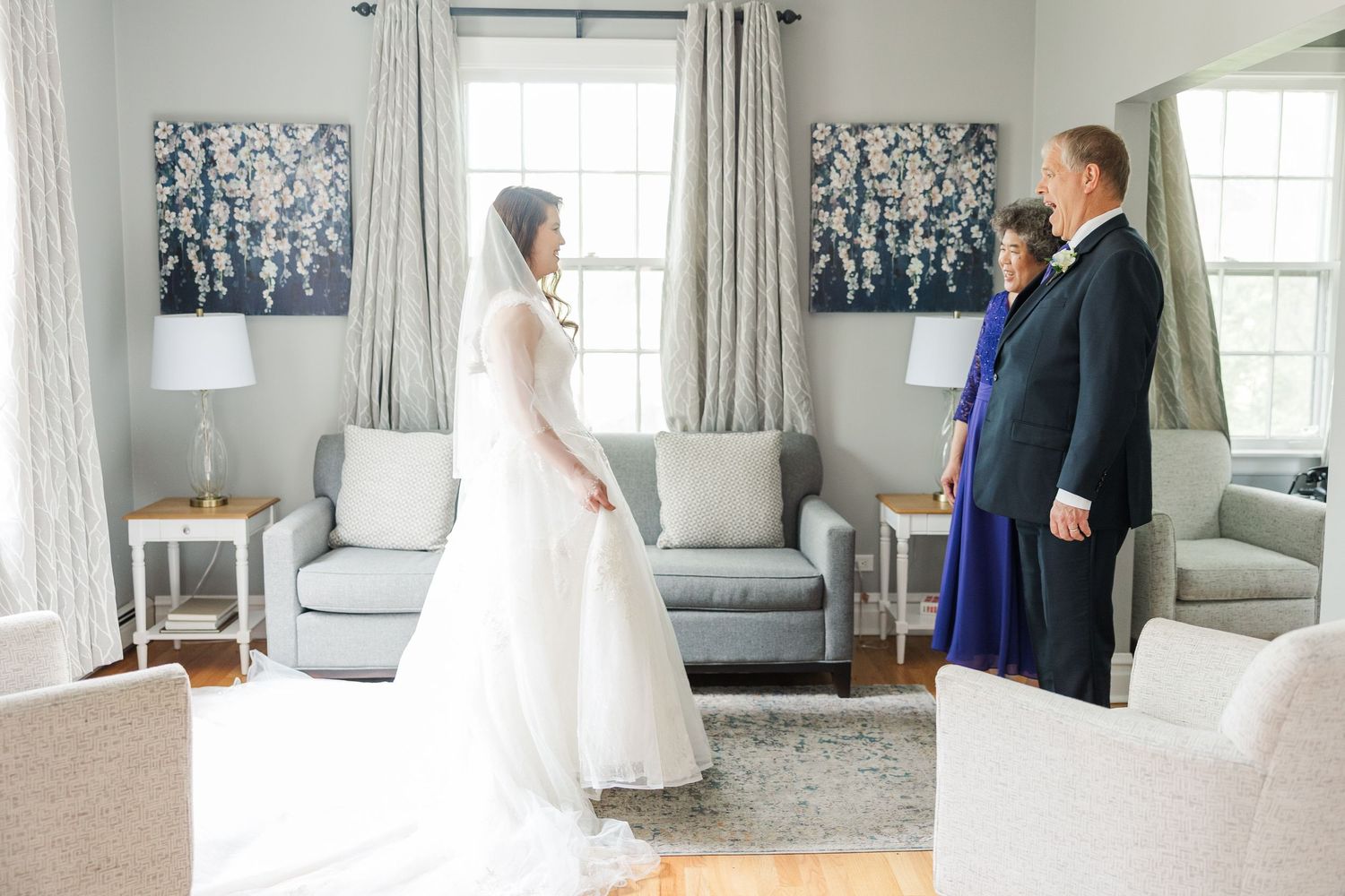 The loving bride shares an emotional first look moment with family members in an elegant light-filled living room.