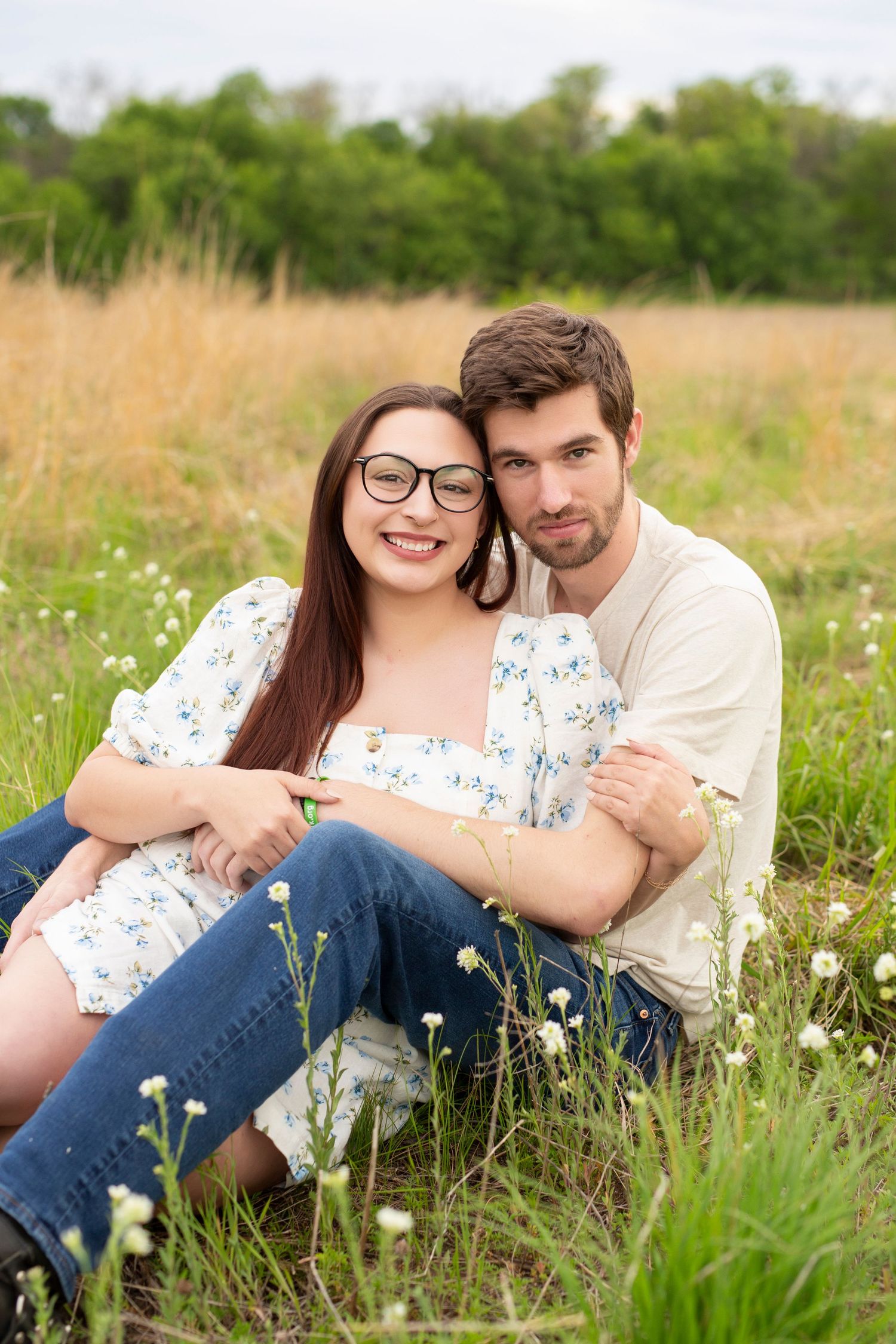 A couple lying together in a wildflower meadow wearing casual clothes during a romantic outdoor photoshoot.