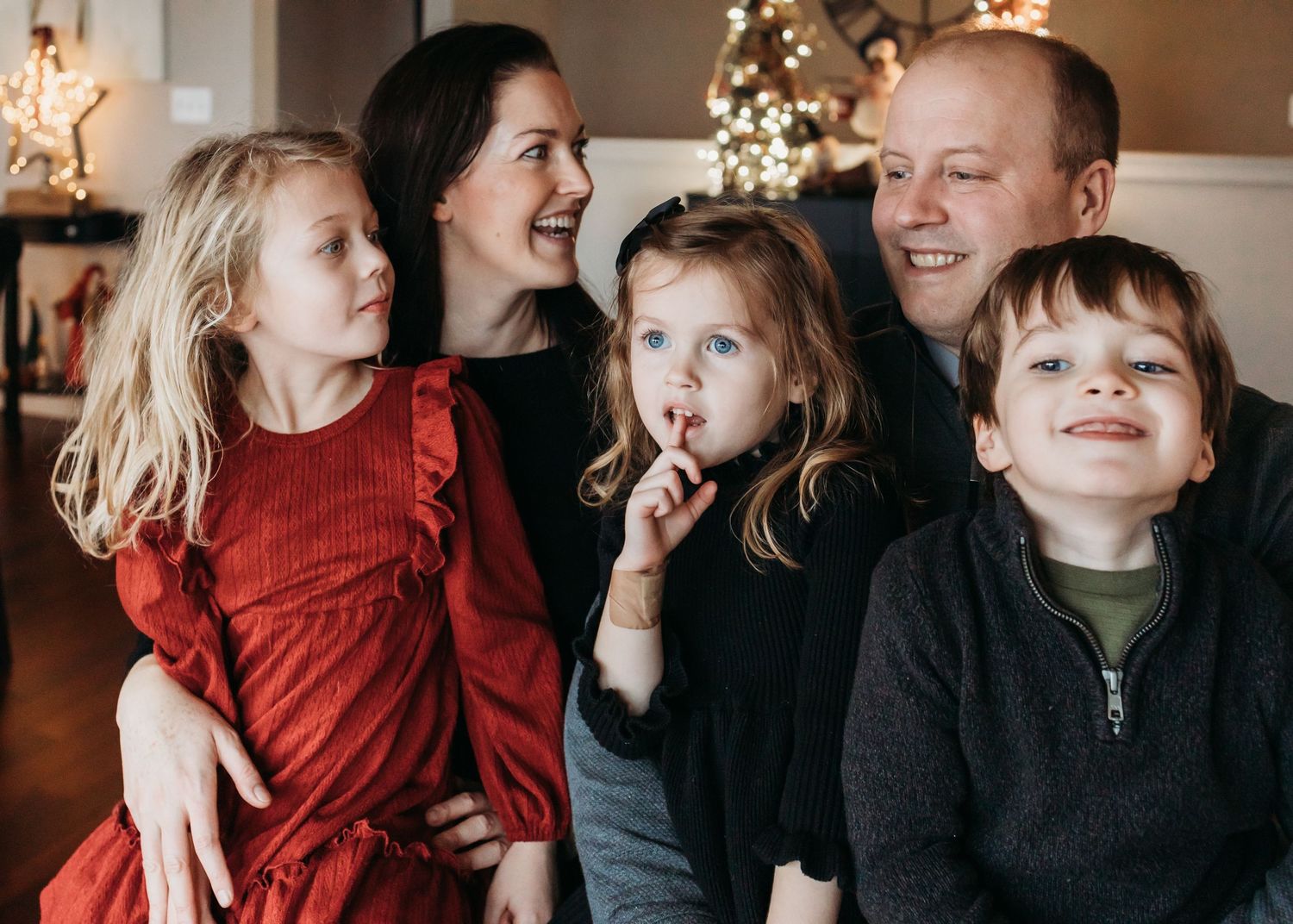 A family wearing red and black clothing shares a candid moment together during Christmas at home.