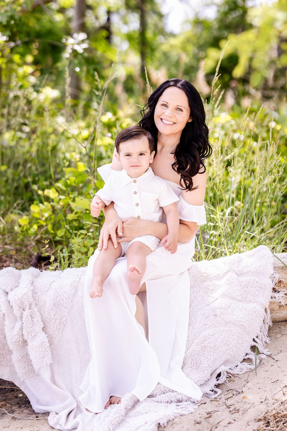 Series of family portraits with baby and parent sitting together in white dresses among lush greenery and sunlit forest.