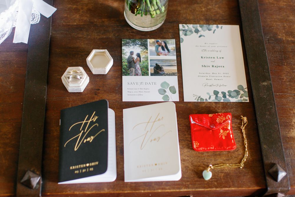 Wedding stationary and vows displayed on wooden table with eucalyptus details and gold foil lettering.