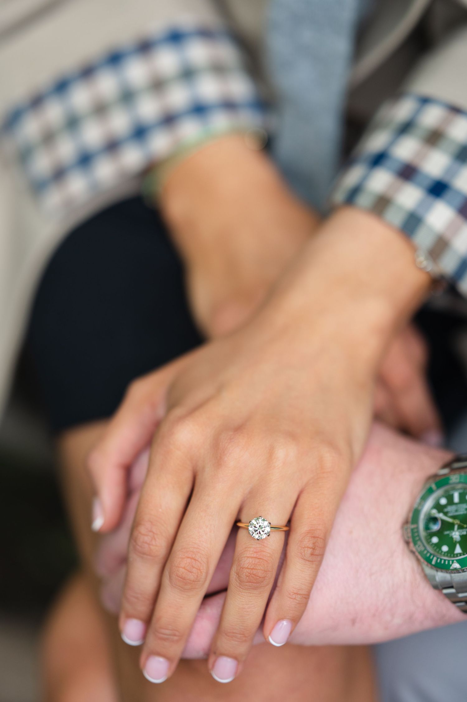 A hand wearing a round solitaire diamond engagement ring from Tiffany's.