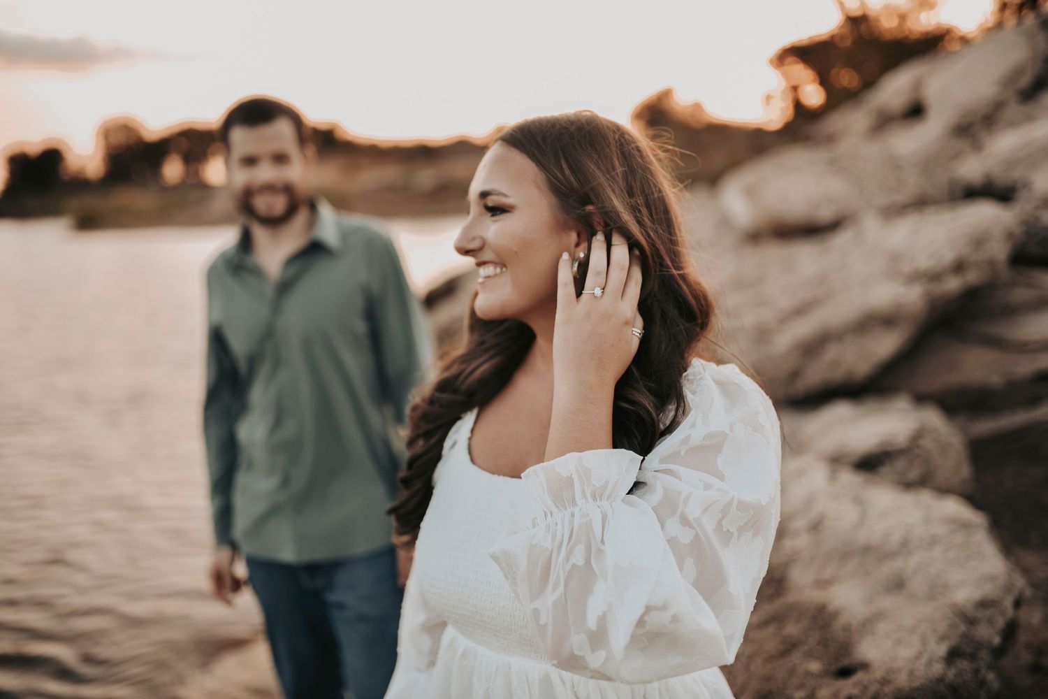 She shows off her engagement diamond as she looks at the lake during the golden hour