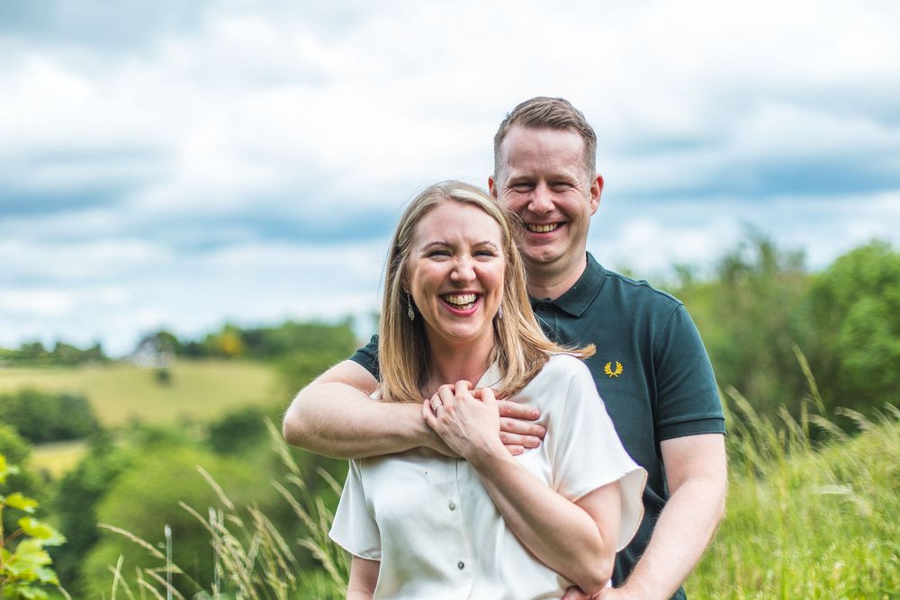 A happy couple enjoys playful moments together outdoors in a summer field.