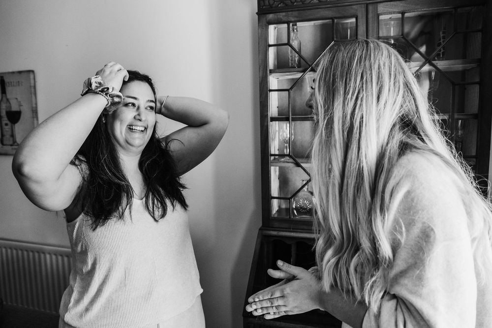 black and white photo of lady fixing her hair while laughing with a friend