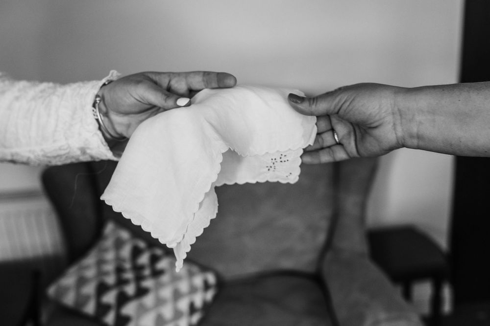 Black and white photo showing hands exchanging a handkerchief or napkin across a table.