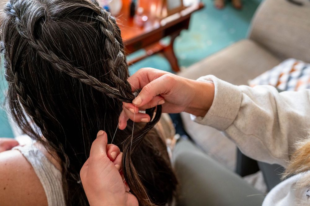 A close-up view showing a bride getting her hait plaited the morning of her wedding