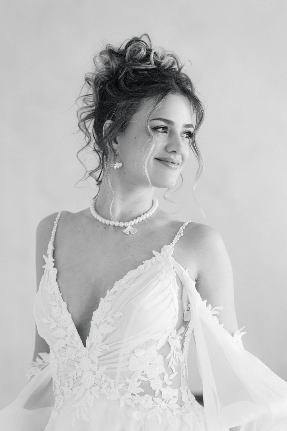 An elegant portrait in black and white showcasing bridal jewelry and a detailed lace gown.