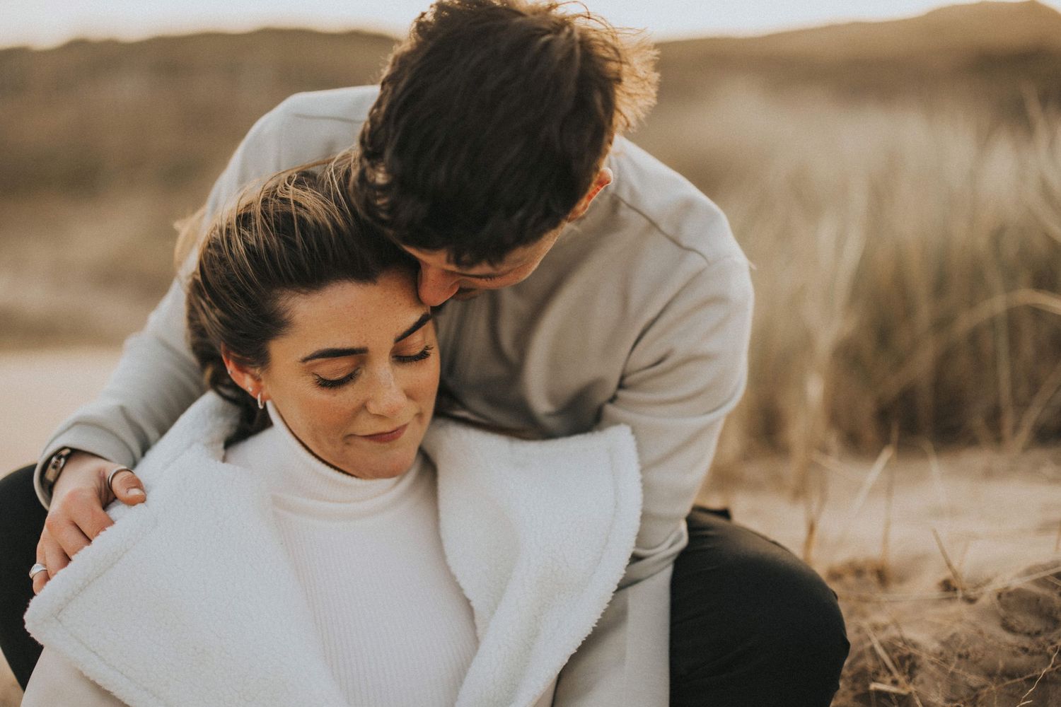 Romantic couple at Cleethorpes beach during golden hour as sunlight creates a dreamy atmosphere. Captured by Lincolnshire photographers.